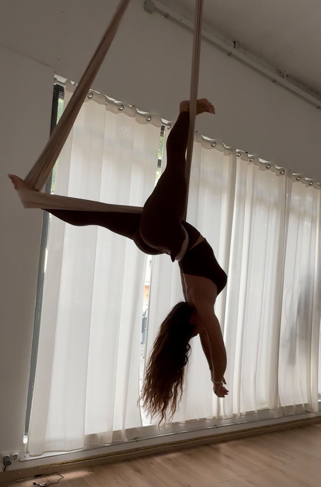 Alumna en hamaca aérea, figura invertida a contraluz